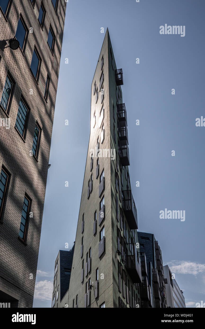Amsterdam, the Netherlands - June 30, 2019: Trangular high rise office building and hotel ending in ultra sharp corner set against blue sky and hit by Stock Photo