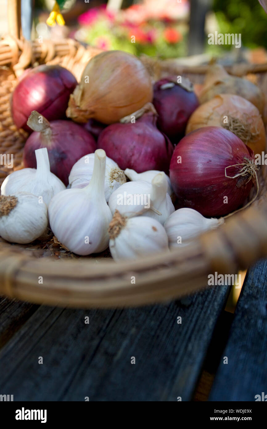 Onions and garlic in basket on table Stock Photo