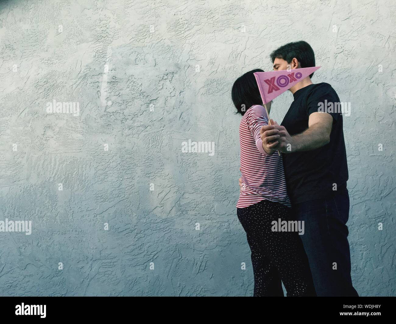 Couple Kissing Against Wall Stock Photo Alamy
