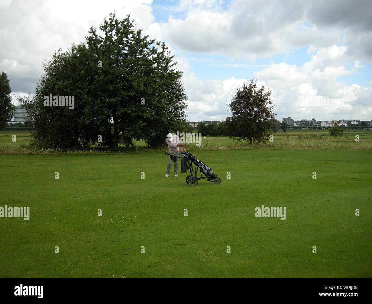 Golfer Taking Shot At Course Against Sky Stock Photo