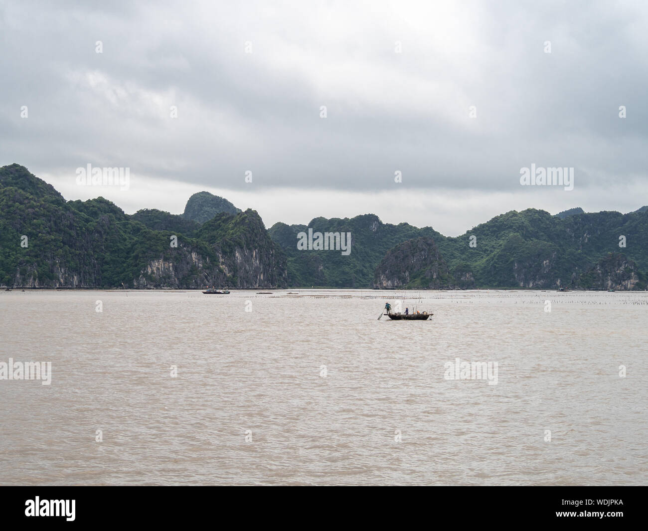 Fishing boats on the water in Ha Long Bay, Vietnam, with limestone rocks behind Stock Photo