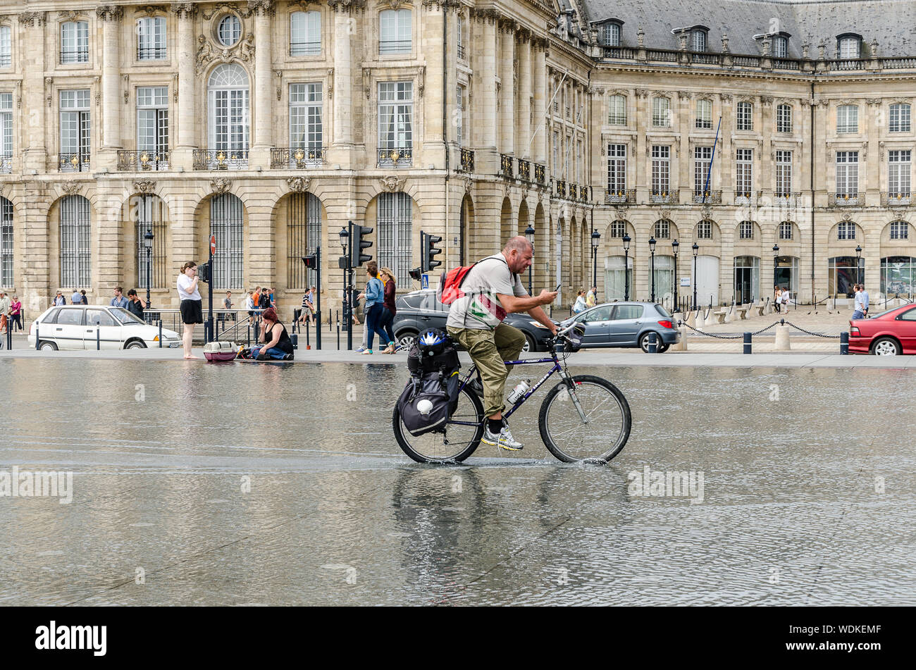 Men bike through the water mirror of the Place de la Bourse in Bordeaux. September 2013. France Stock Photo