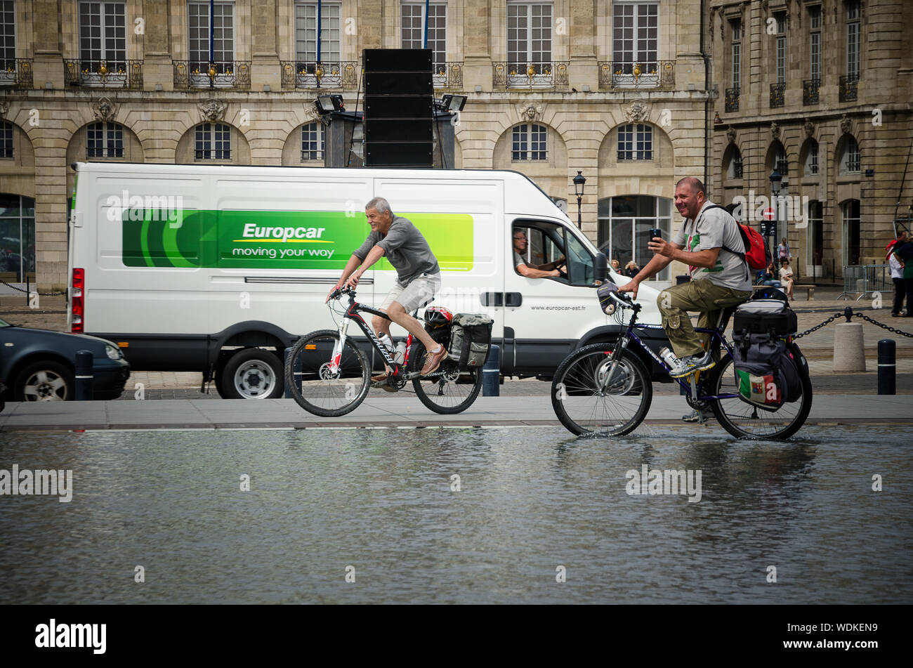 Men bike through the water mirror of the Place de la Bourse in Bordeaux. September 2013. France Stock Photo