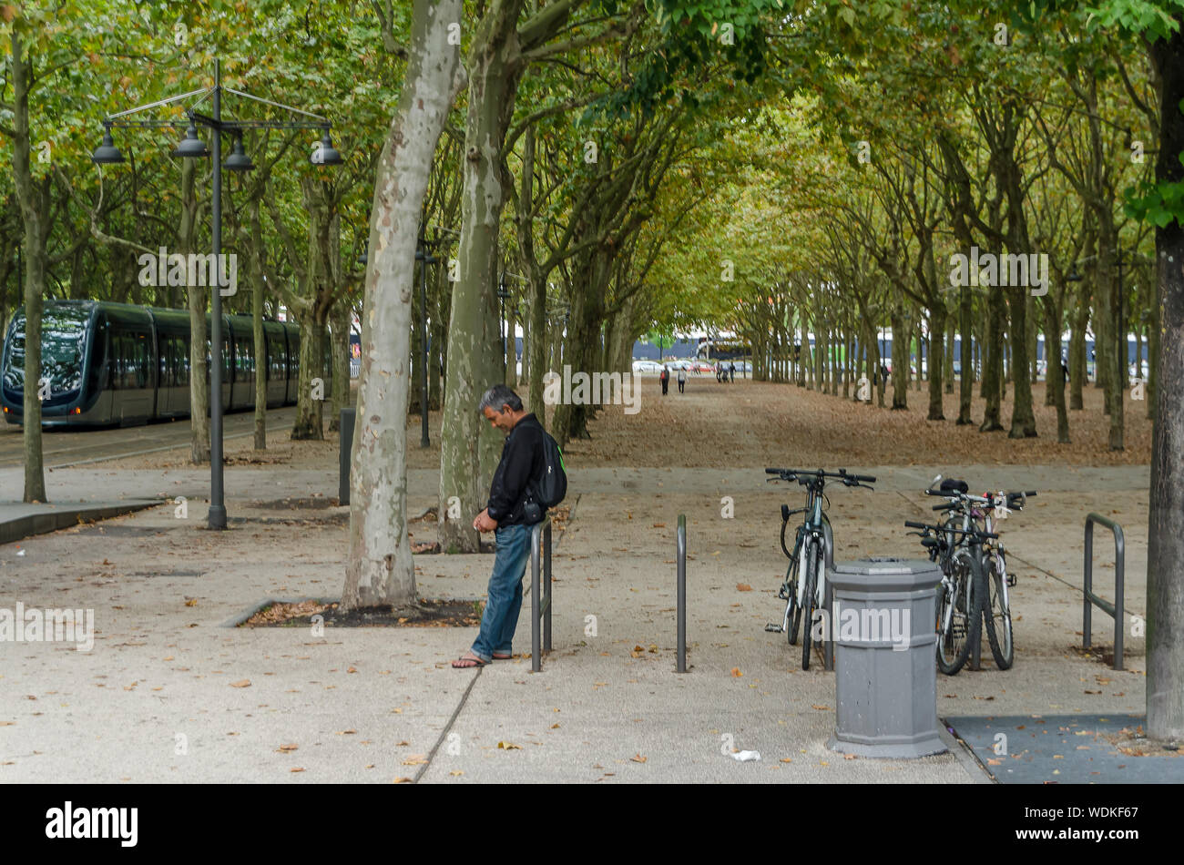 Man leaning on a bike parkin in front of the park in the city of Bordeaux, France, in September 2013 Stock Photo