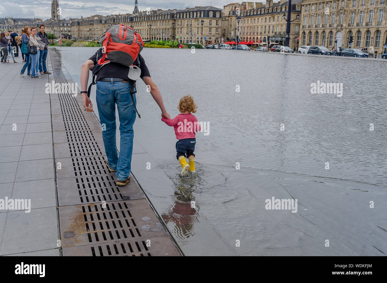 Father and daughter playing in the water mirror of the Place de la Bourse in Bordeaux. September 2013. France Stock Photo