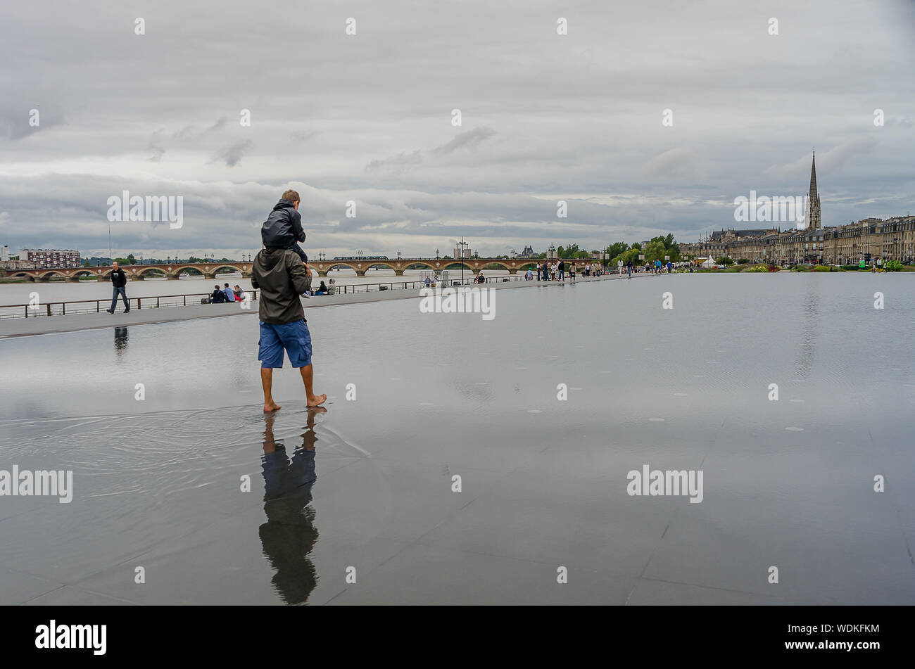 Father and daughter playing in the water mirror of the Place de la Bourse in Bordeaux. September 2013. France Stock Photo