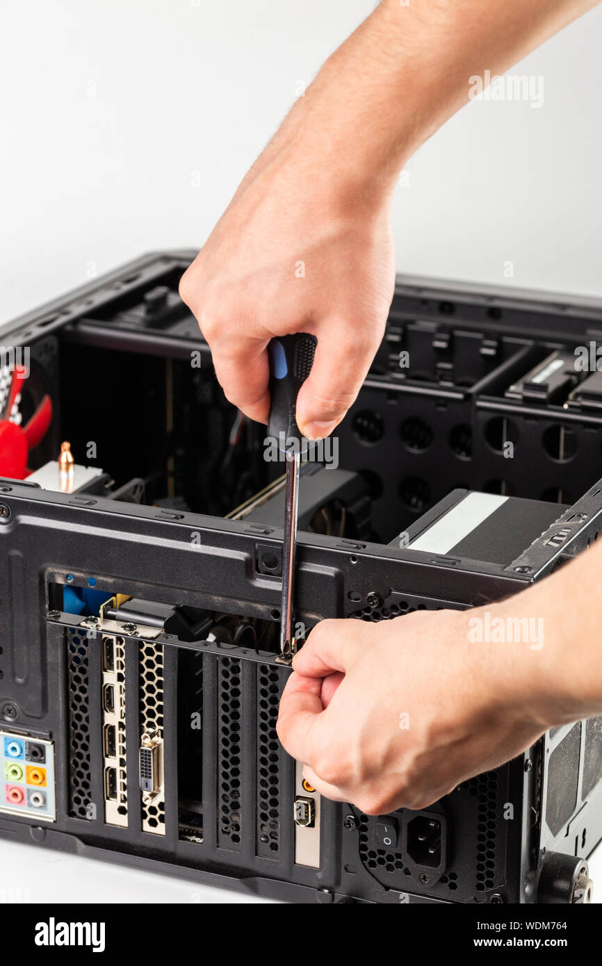 hands unscrewing a video card bracket while maintenance personal computer hardware with selective focus closeup Stock Photo