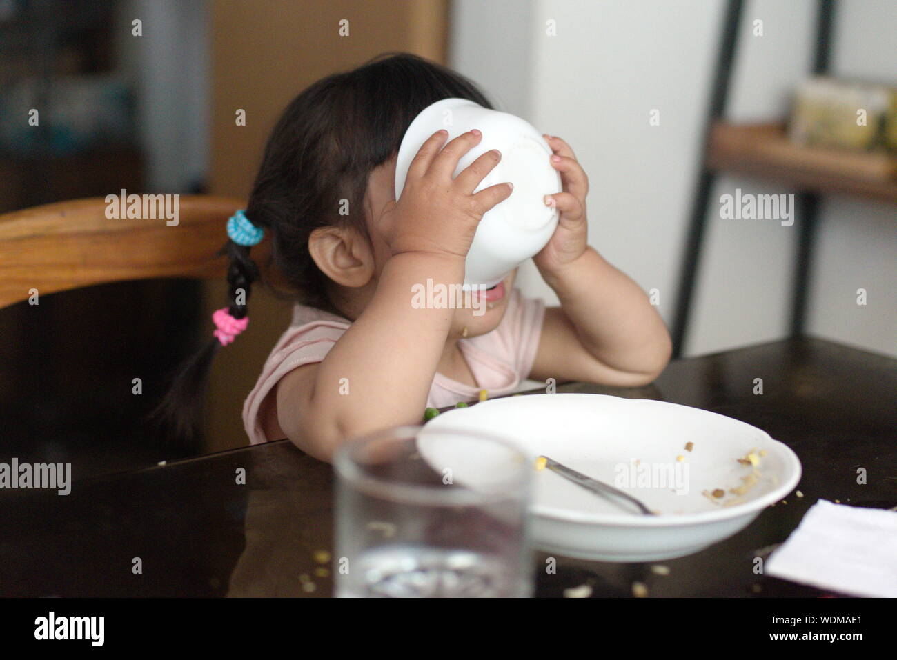 Toddler girl eating all her food and empty dishes Stock Photo