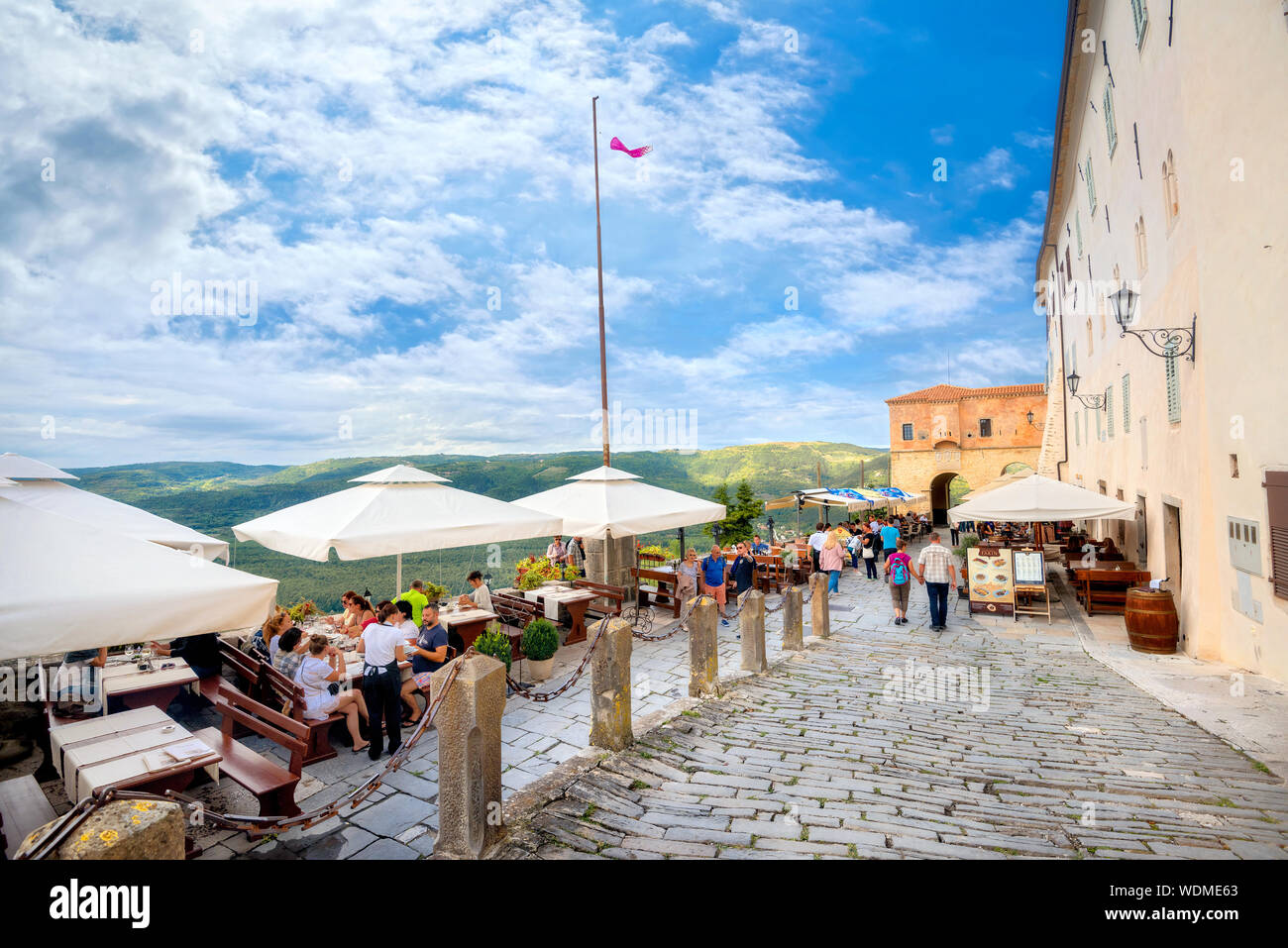 Skyline view over green hills from cafe. Terrace and street with colorful houses of medieval town.Motovun, Croatia, Istria Stock Photo