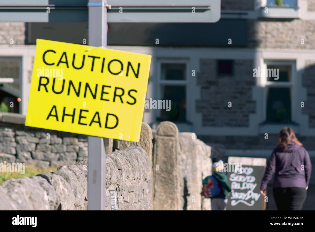 A large yellow sign saying Caution Runners Ahead in a small town Stock ...