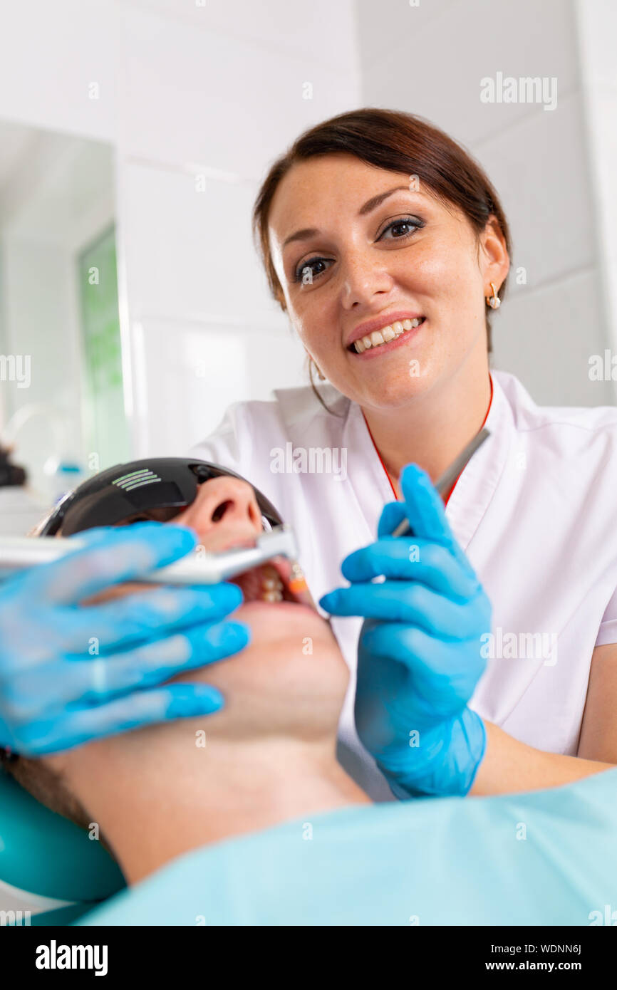 Young man visiting the dental office. Dentist hands in protective