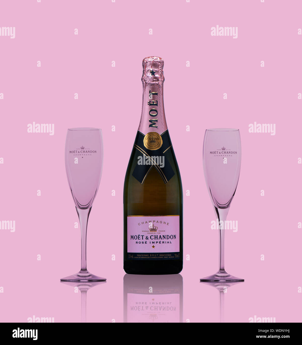 Amsterdam, Hoilland August 2019, Isolated bottle of champain with two glasses against pink background reflecting on the surface Stock Photo