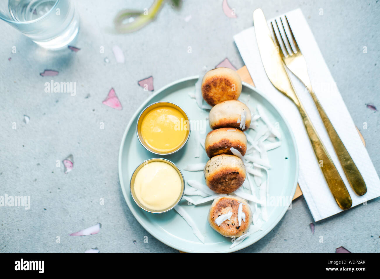 Vegan tofu cheese pancakes on blue plate, gray concrete table. Sun light. Food blog photography concept. Overhead Stock Photo