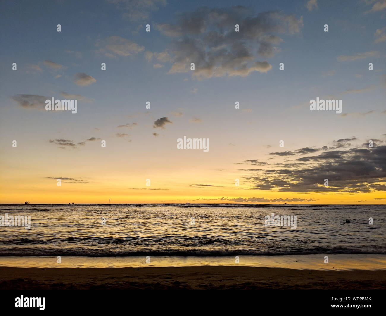 Dusk light reflecting on the Pacific ocean on the water with boats on the water off the beach of Waikiki on Oahu, Hawaii. Stock Photo