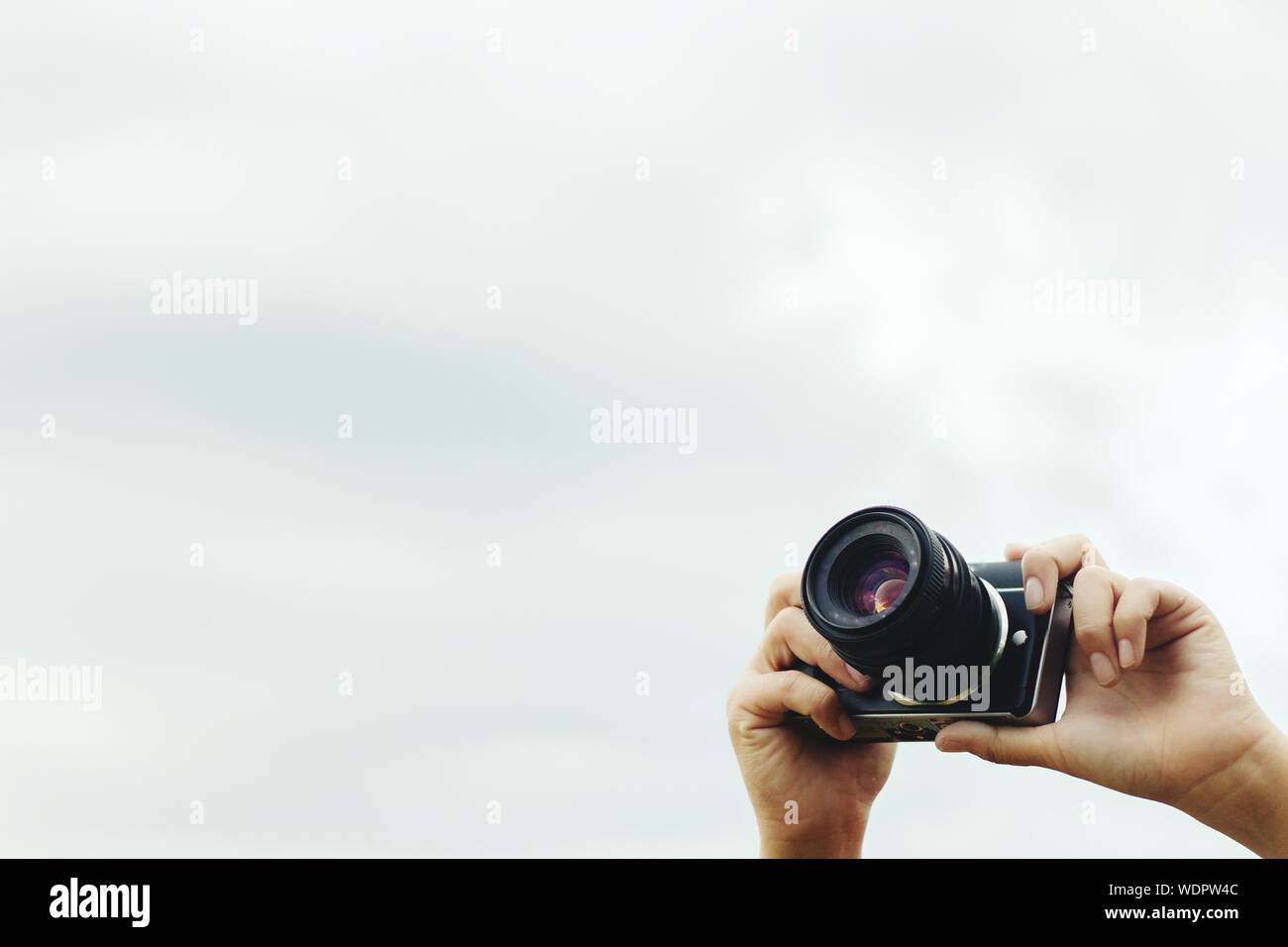 Low Angle View Of Person Photographing With Digital Camera Against Sky Stock Photo
