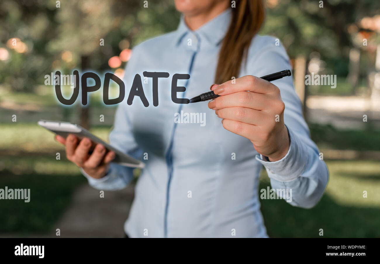 Conceptual hand writing showing UPDATE. Concept meaning make something more modern or up to date like software program Woman in a blue shirt pointing Stock Photo