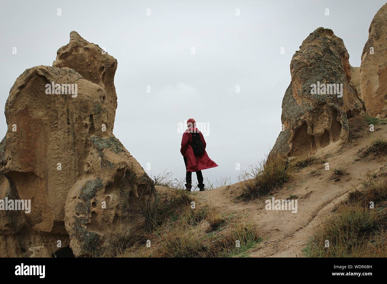 Rear View Of Hiker Amidst Rock Formation Against Sky At Cappadocia Stock Photo