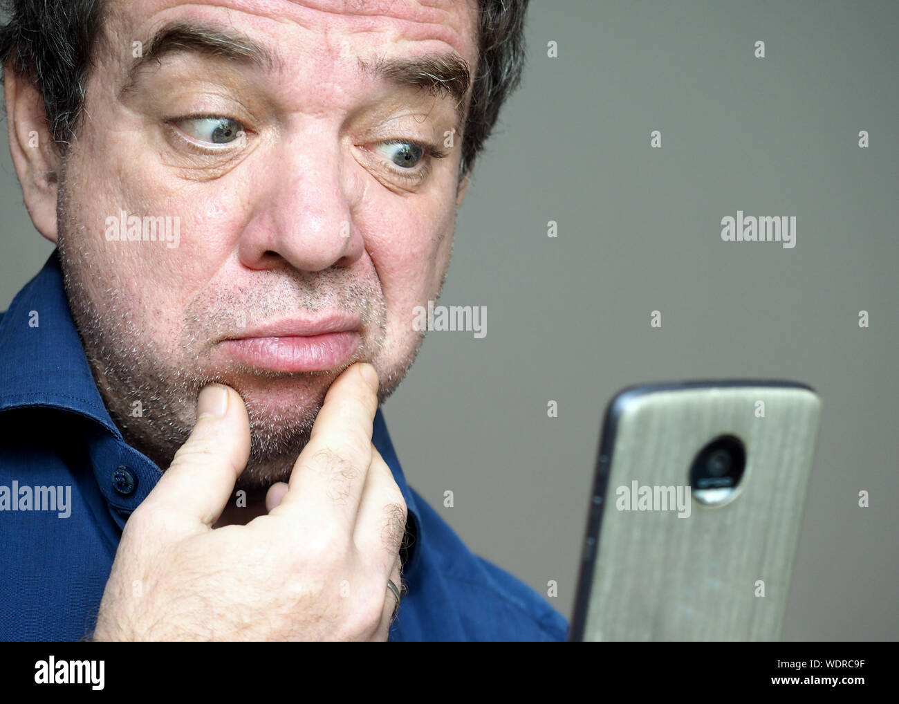 Close-up Of Confused Man Looking At Mobile Phone Stock Photo