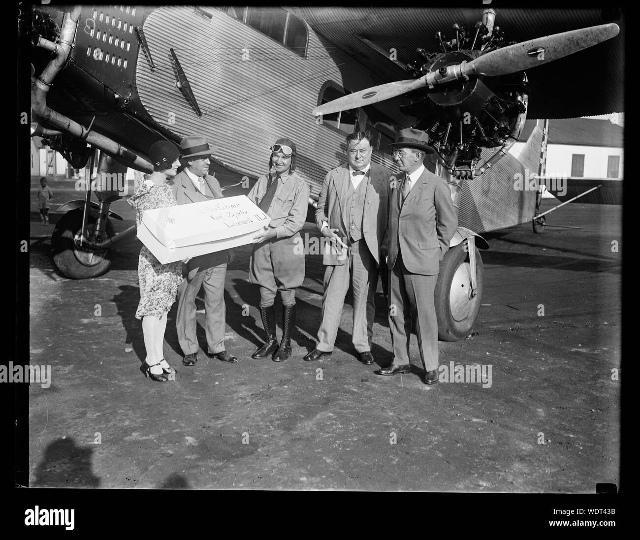 Group next to airplane with package addressed to Dr. Hugo Eckener, Graf-Zeppelin, Lakehurst, N.J. Abstract/medium: 1 negative : glass  4 x 5 in. or smaller Stock Photo