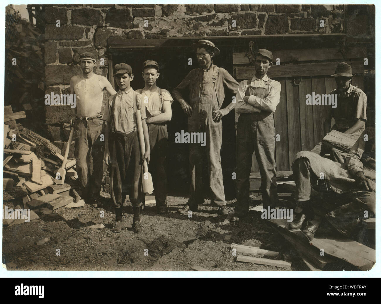 Group outside Pittman Handle Factory. A fifteen year old boy operating a dangerous boring machine at which he said a boy recently bored half his hand off. To operate this machine (which bores a large hole in the spade handle) the boy has to throw his whole weight onto the lever which pushes the handle (and himself) up against the unprotected borer. A slip might easily result fatally. Boy earns $1.65 a day. This factory has a number of unprotected belts and dangerous machines. One other boy, about the age of this one, was doing all kind[s] of work, taking away the handles from a huge rip saw, e Stock Photo