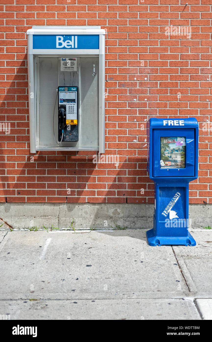 Pay phone and newspaper box by brick wall Stock Photo