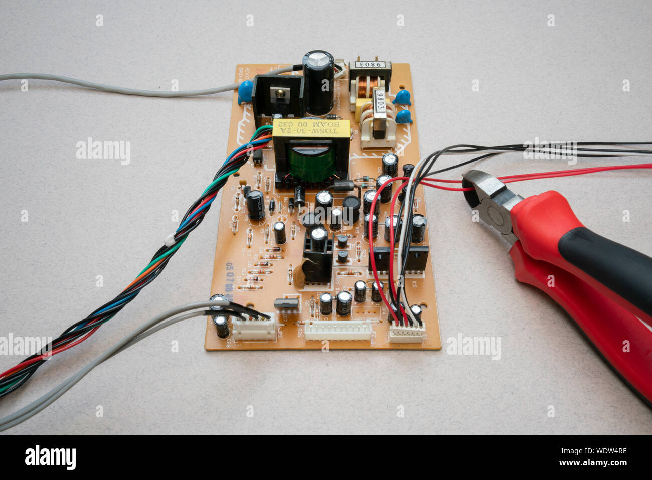 a circuit board with wires and a set of wire cutters cutting a wire Stock Photo