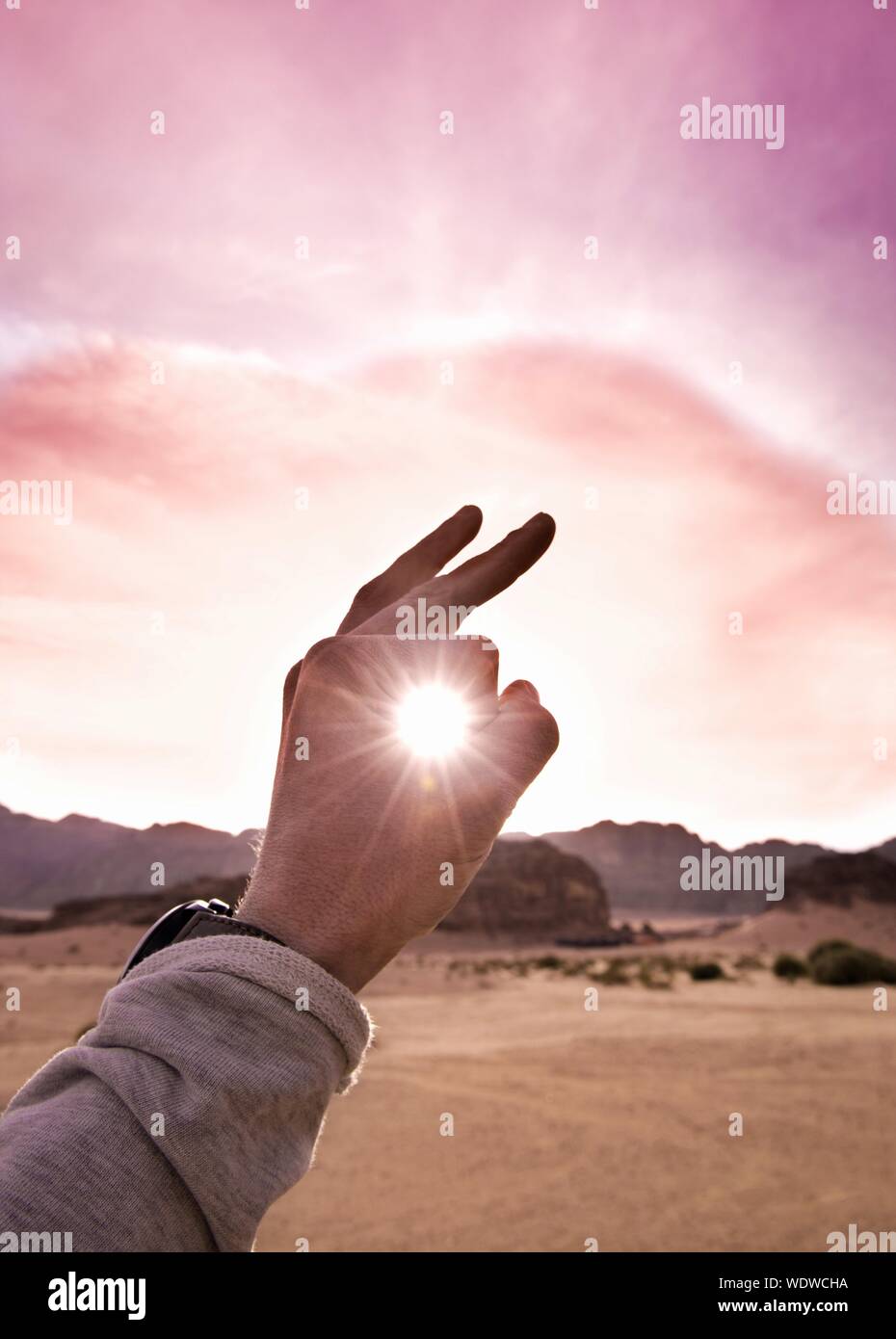 Optical Illusion Of Hand Holding Sun Against Sky Stock Photo