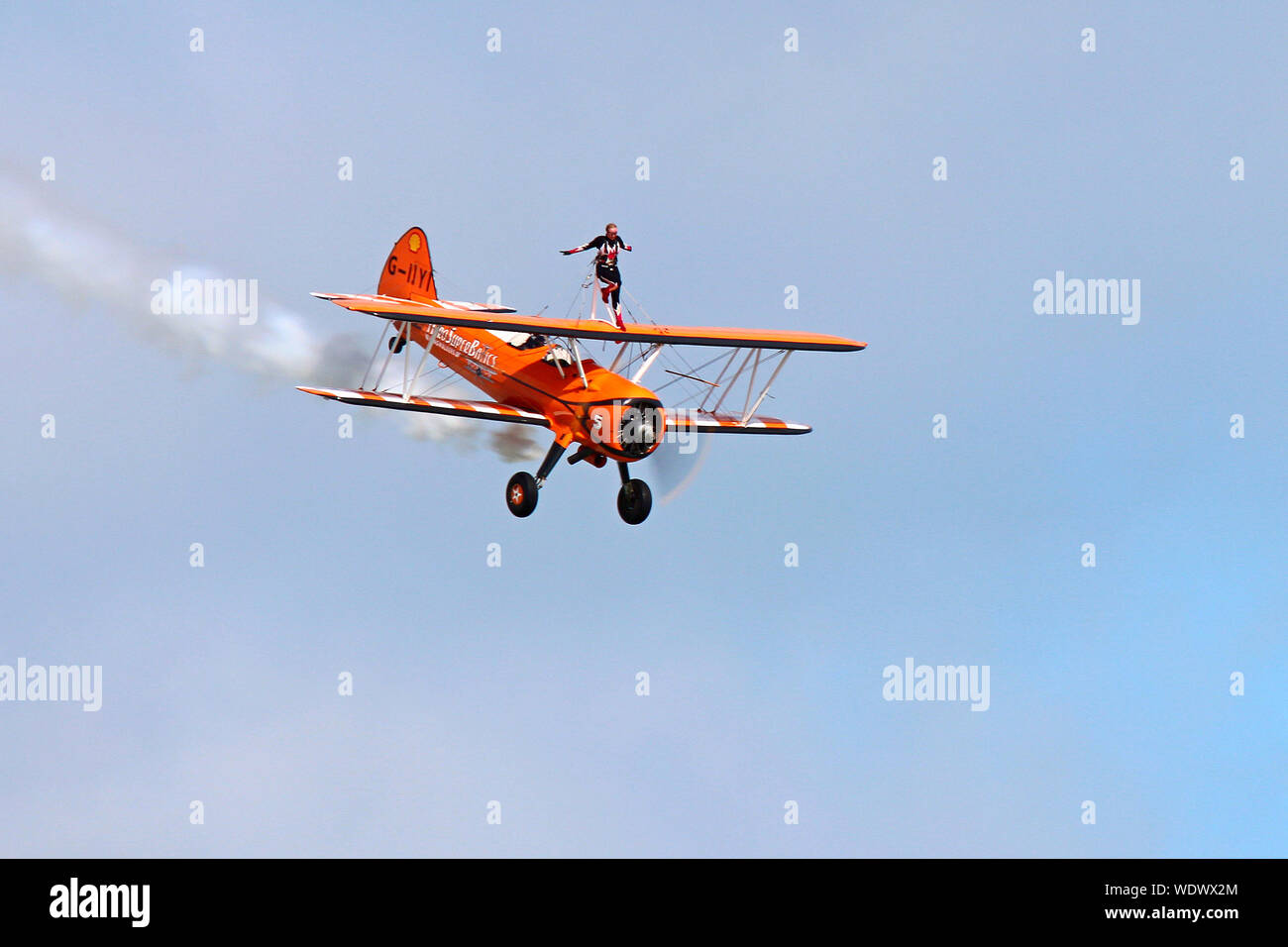 Part of the Aerosuperbatics Wingwalkers this 1940's biplane with the young lady strapped on top wows the crowd at Eastbourne's International Airshow. Stock Photo