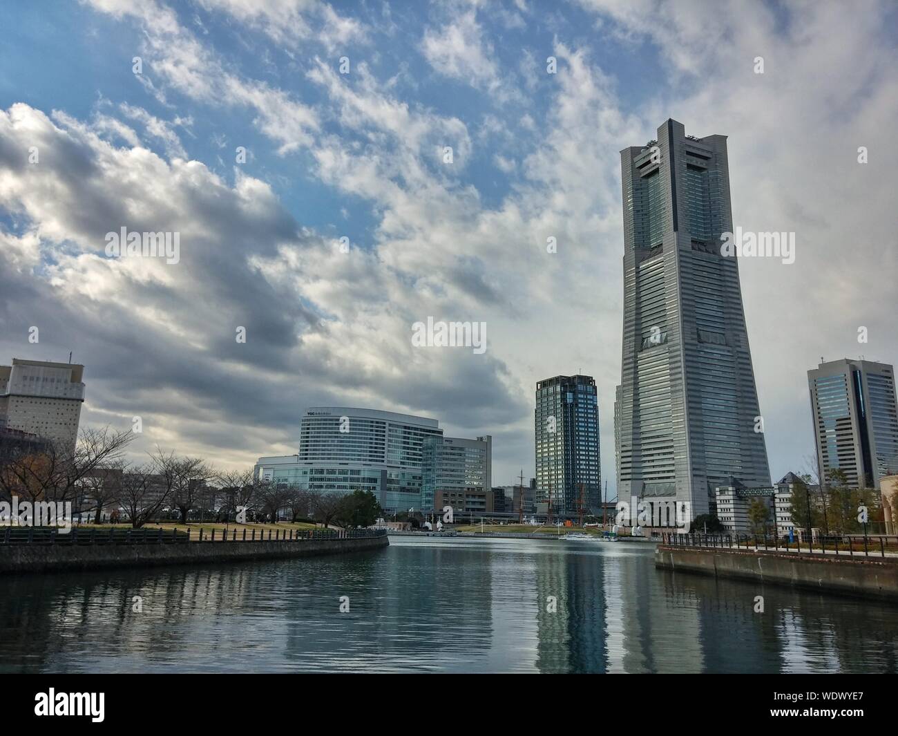 Yokohama Landmark Tower And Buildings By Canal Against Sky Stock Photo