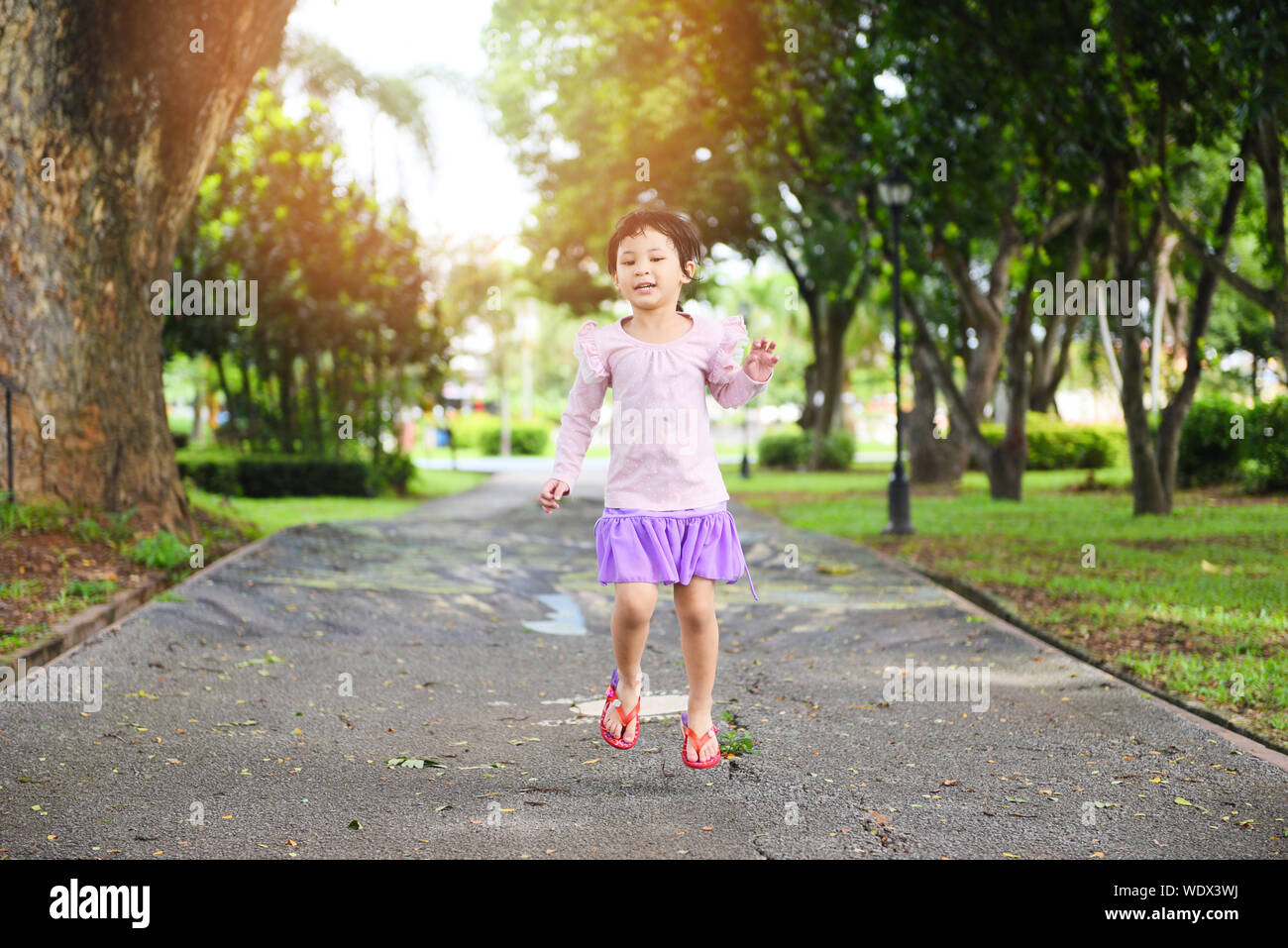 Child having fun playing outside Asian kid girl happy jumping in the ...