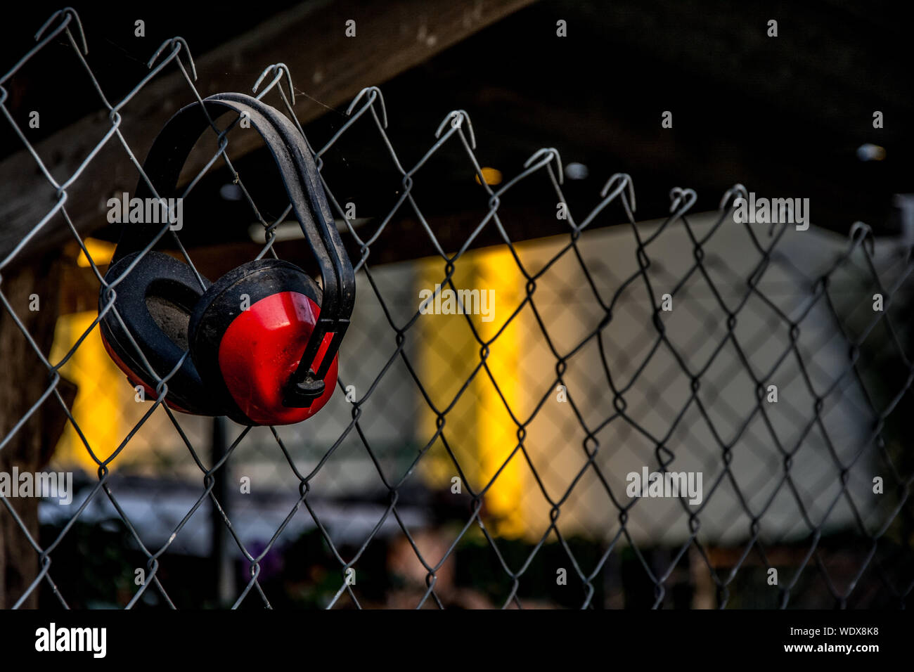 Close-up Of Earmuffs Hanging Chainlink Fence Stock Photo