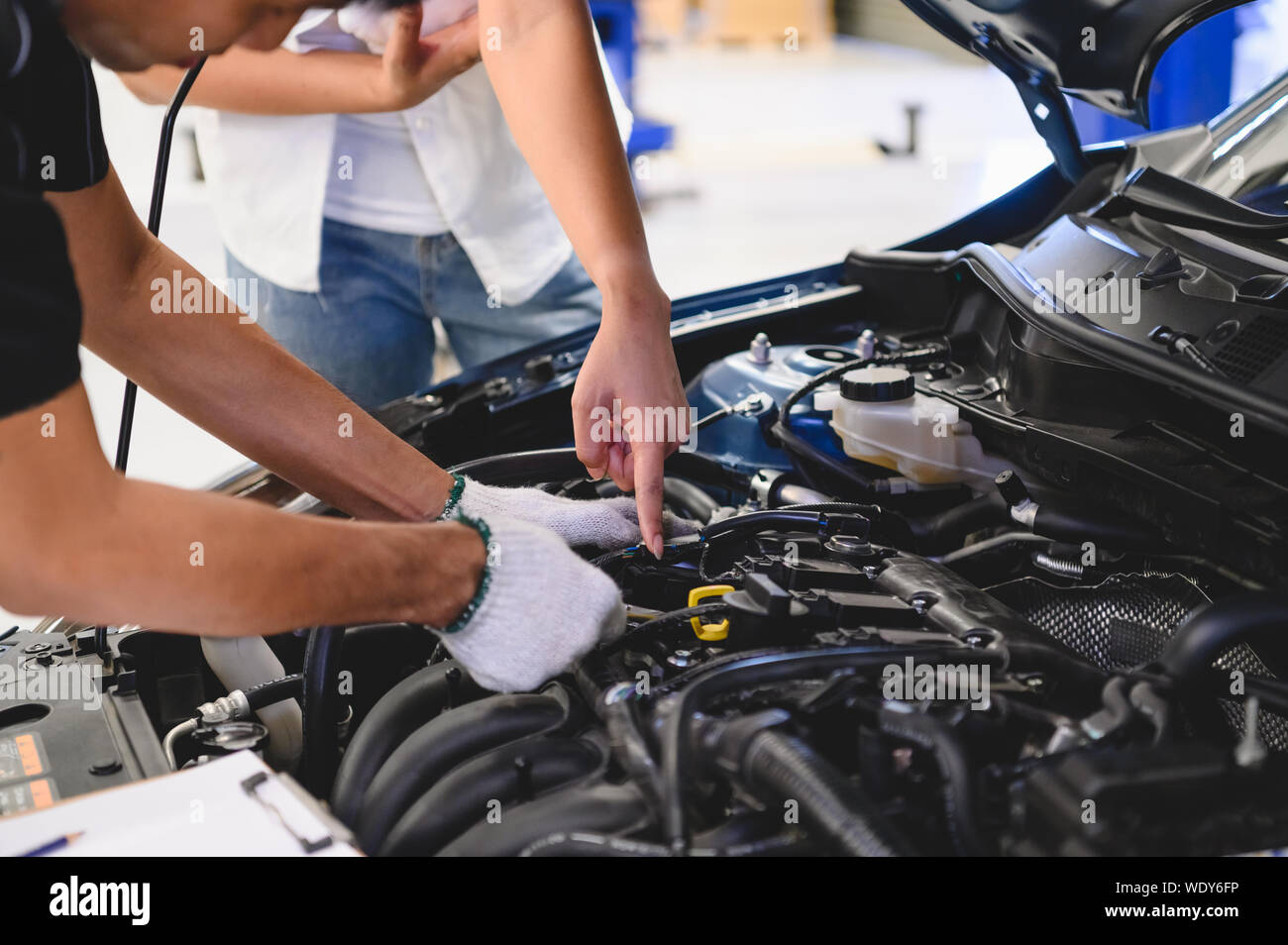 Asian male auto mechanic examine car engine breakdown problem in front of  automotive vehicle car hood with female customer. Safety technical  inspectio Stock Photo - Alamy