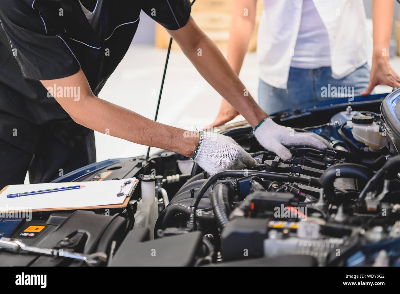 Asian male auto mechanic examine car engine breakdown problem in front