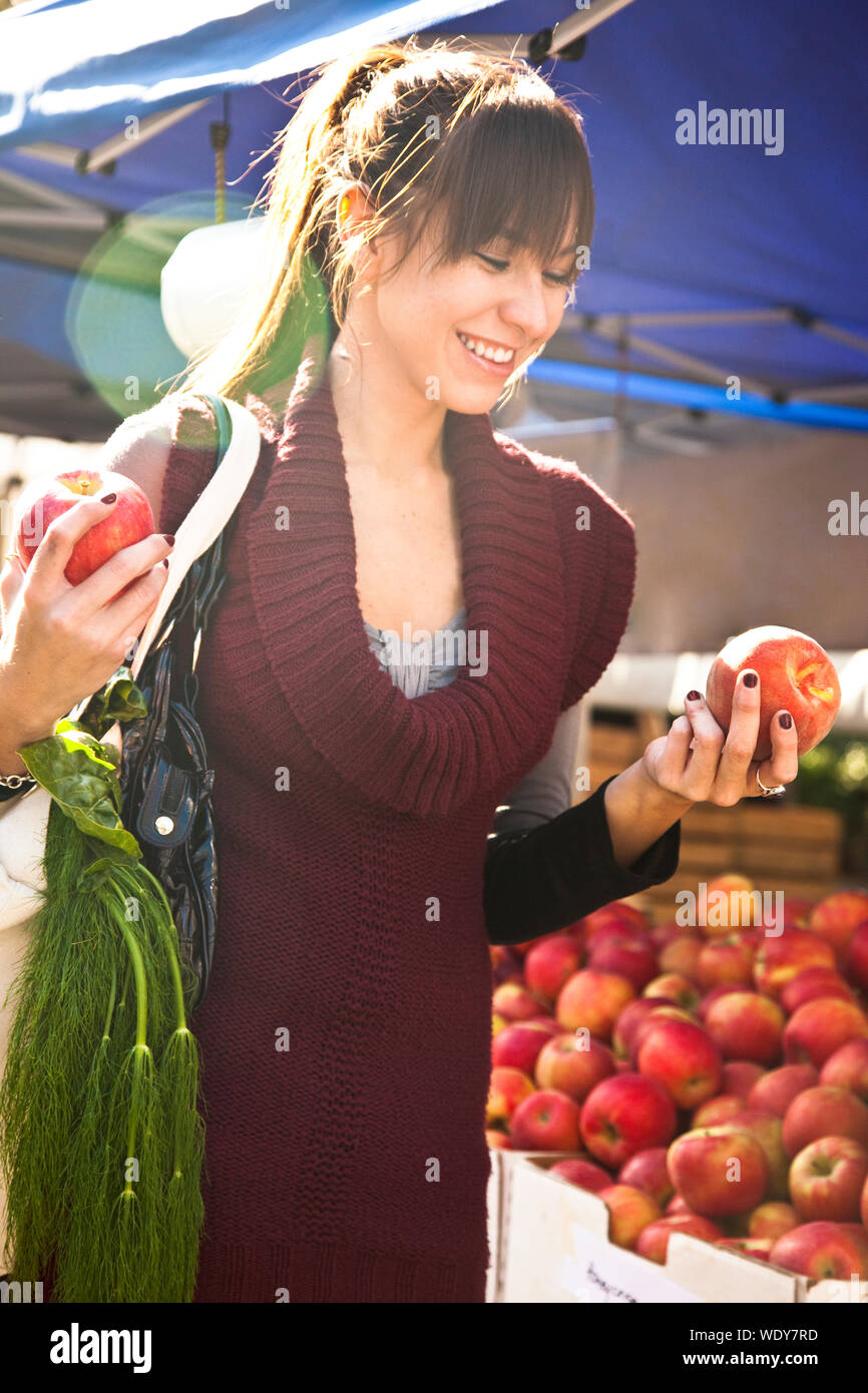 Happy, smilling, young Hispanic woman shopping for fresh fruit produce at farmers market. Healthy lifestyles. Stock Photo