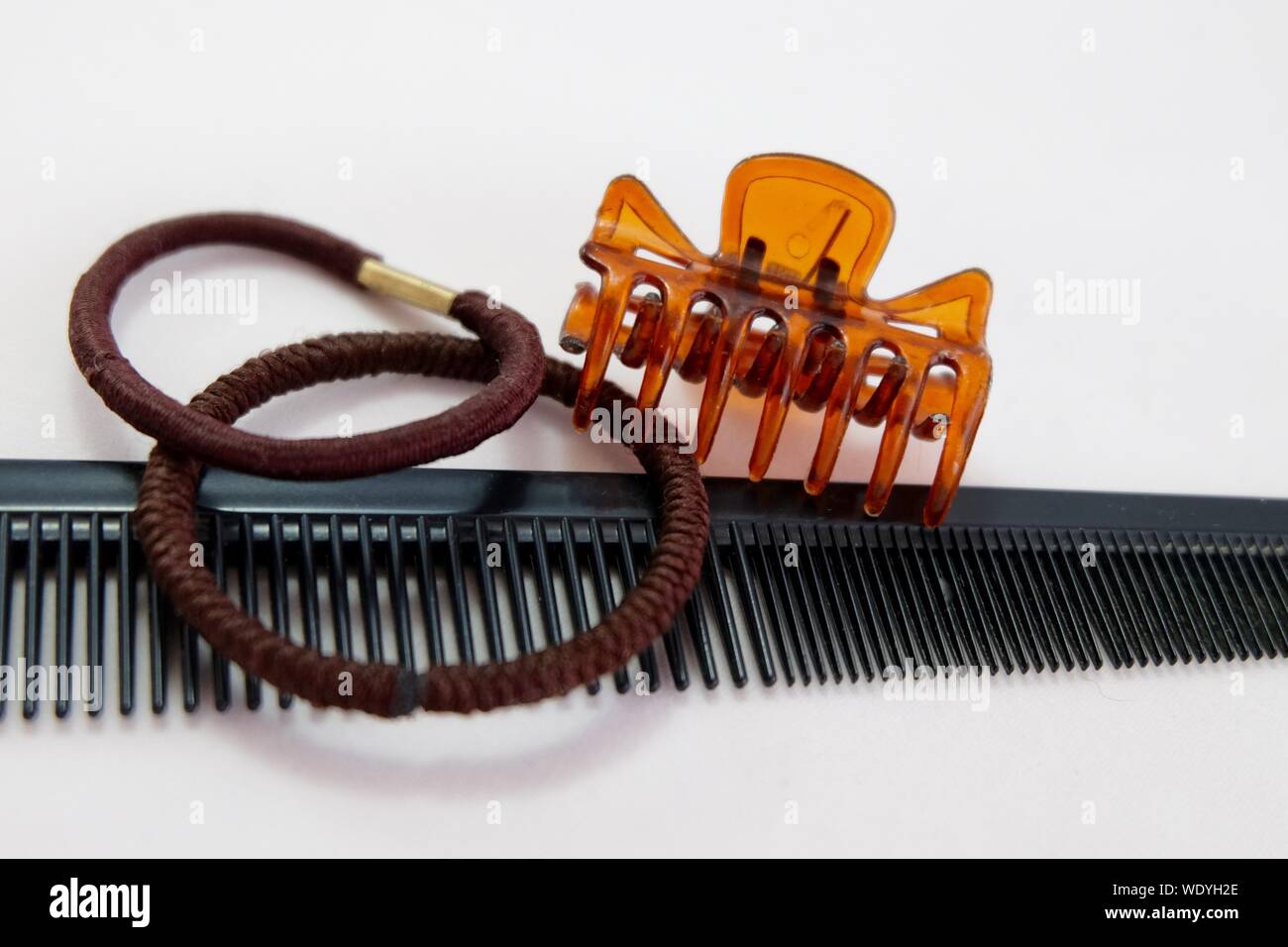 Close-up Of Comb With Hair Clip And Rubber Bands On White Background Stock Photo