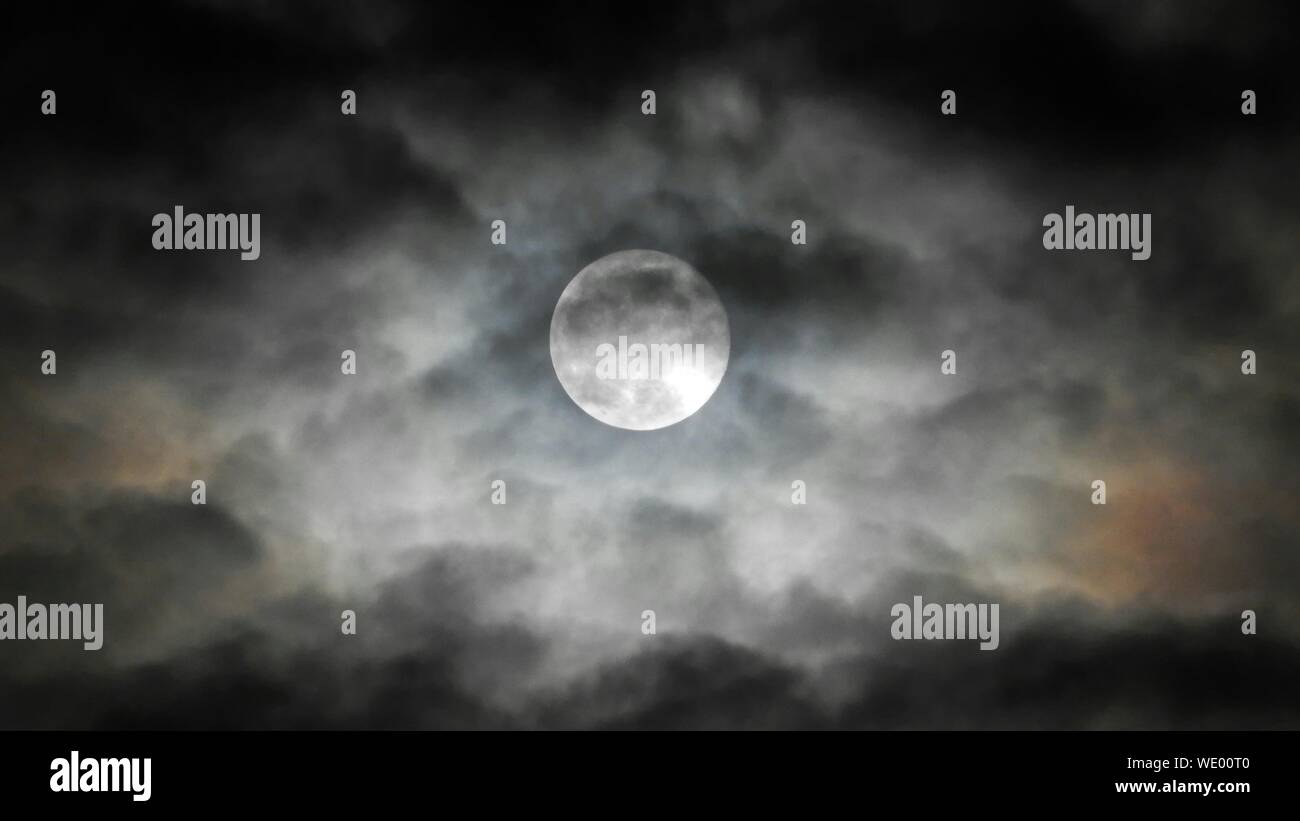 Idyllic View Of Moon Covered With Black Clouds At Night Stock Photo