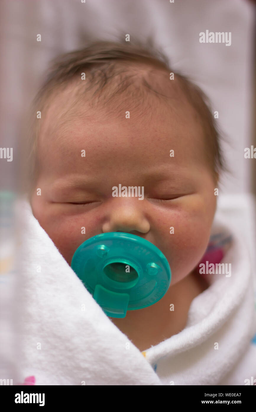 Close-up Of Newborn Baby With Green Pacifier In Hospital Stock Photo