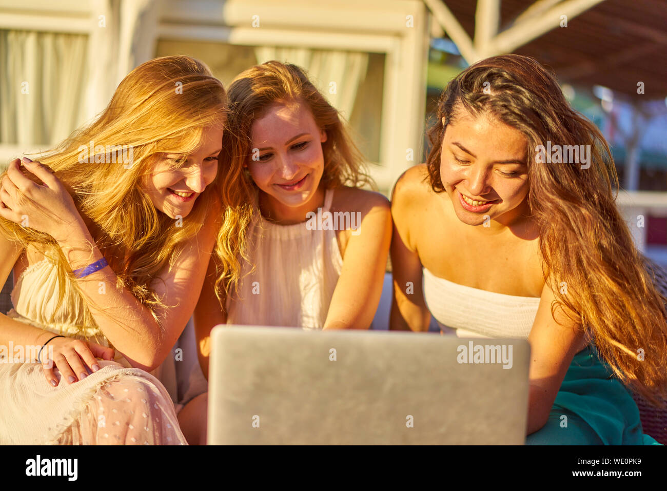 Smiling Friends Using Laptop Against House Stock Photo