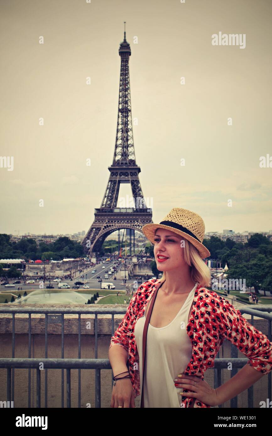 Beautiful Woman With Hand On Hip Standing By Eiffel Tower Against Clear Sky Stock Photo Alamy