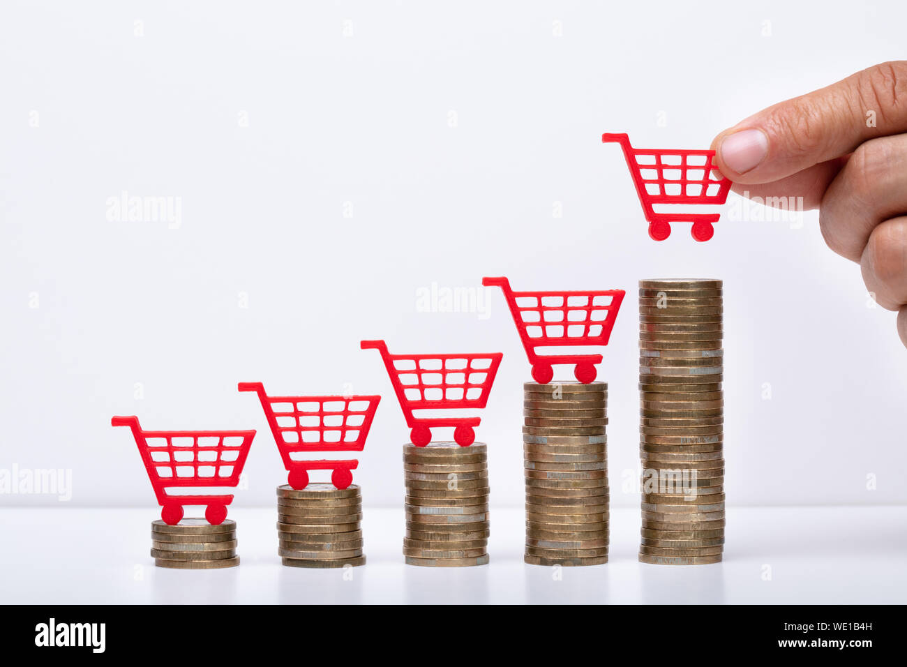 Midsection Of Businessman Placing Shopping Cart On Stacked Coins In Increasing Order Stock Photo