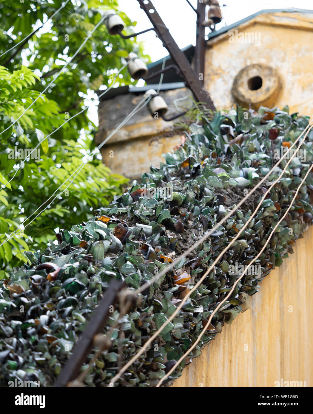 Broken glass and electrified wire atop a wall surrounding the Hanoi Hilton or Hoa Lo Prison in Hanoi Vietnam Stock Photo
