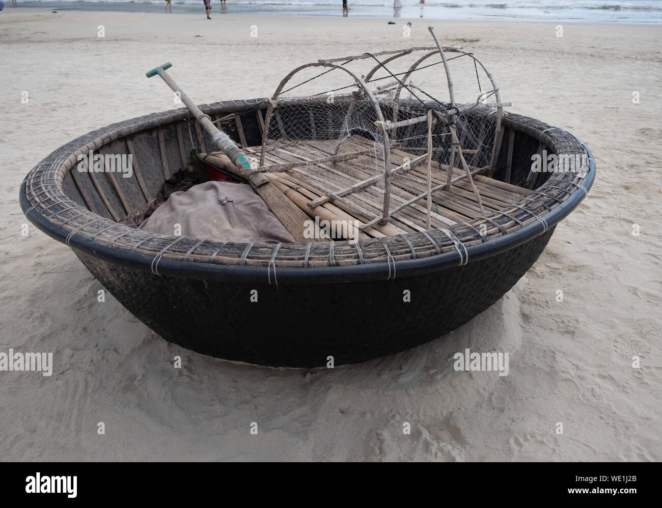Close up of a Vietnamese fishing basket boat with oar and net trap on the beach in Danang. Stock Photo