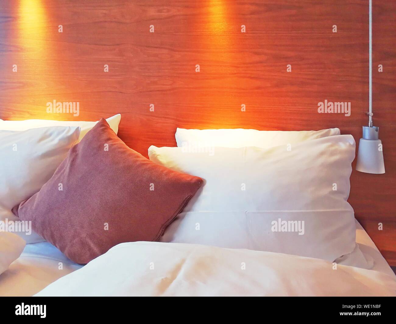 Pillows On Bed Against Illuminated Headboard In Bedroom Stock Photo - Alamy