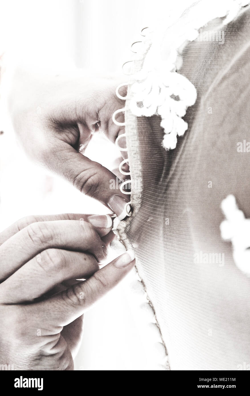 Cropped Hands Of Woman Assisting Bride In Getting Ready Stock Photo