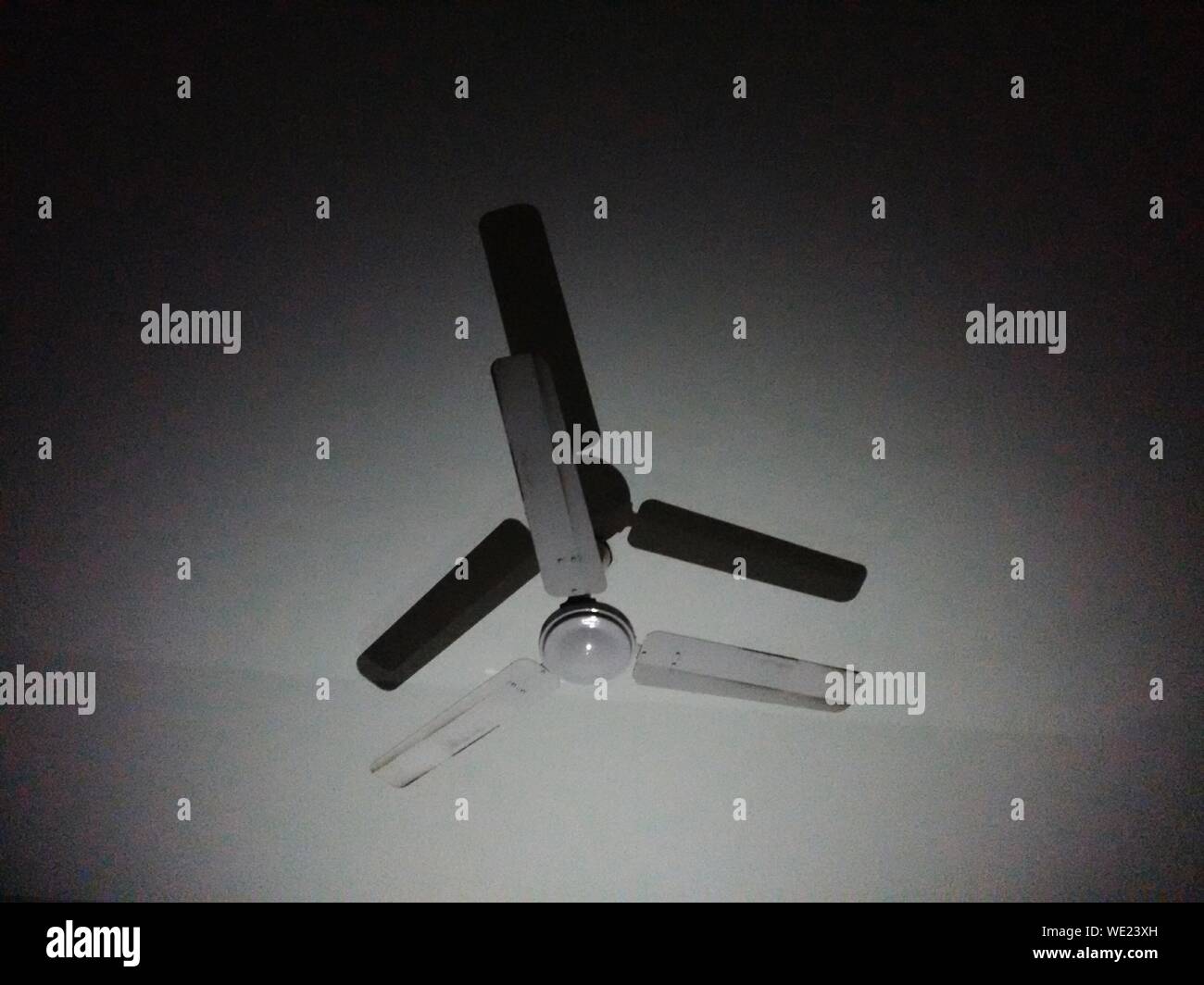 Low Angle View Of Ceiling Fan Hanging From Ceiling In Darkroom