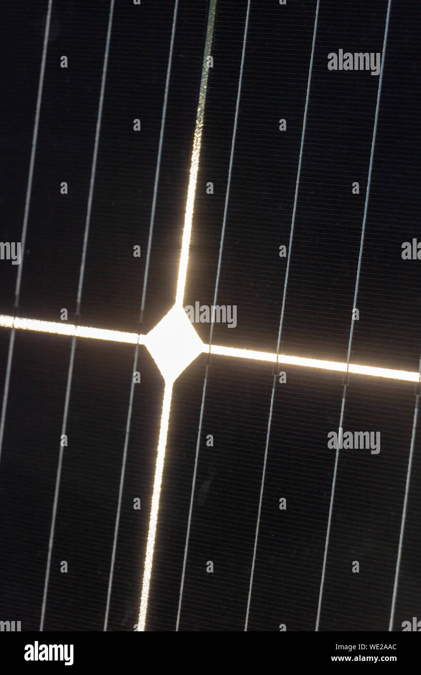 Close-up of a photovoltaic cell receiving sunlight and whose reflection forms a Christian luminous cross Stock Photo