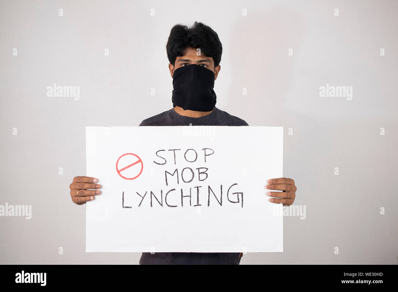 Young man protesting against the Mob lynching by holding Placard showing of Stop Mob Lynching on isolated background. Stock Photo