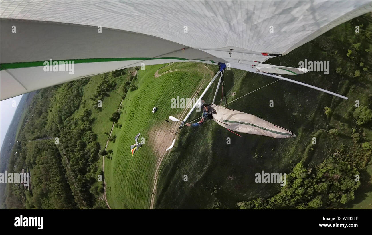 Hang glider pilotfly above green hills on low altitude. Extreme aviation sport Stock Photo