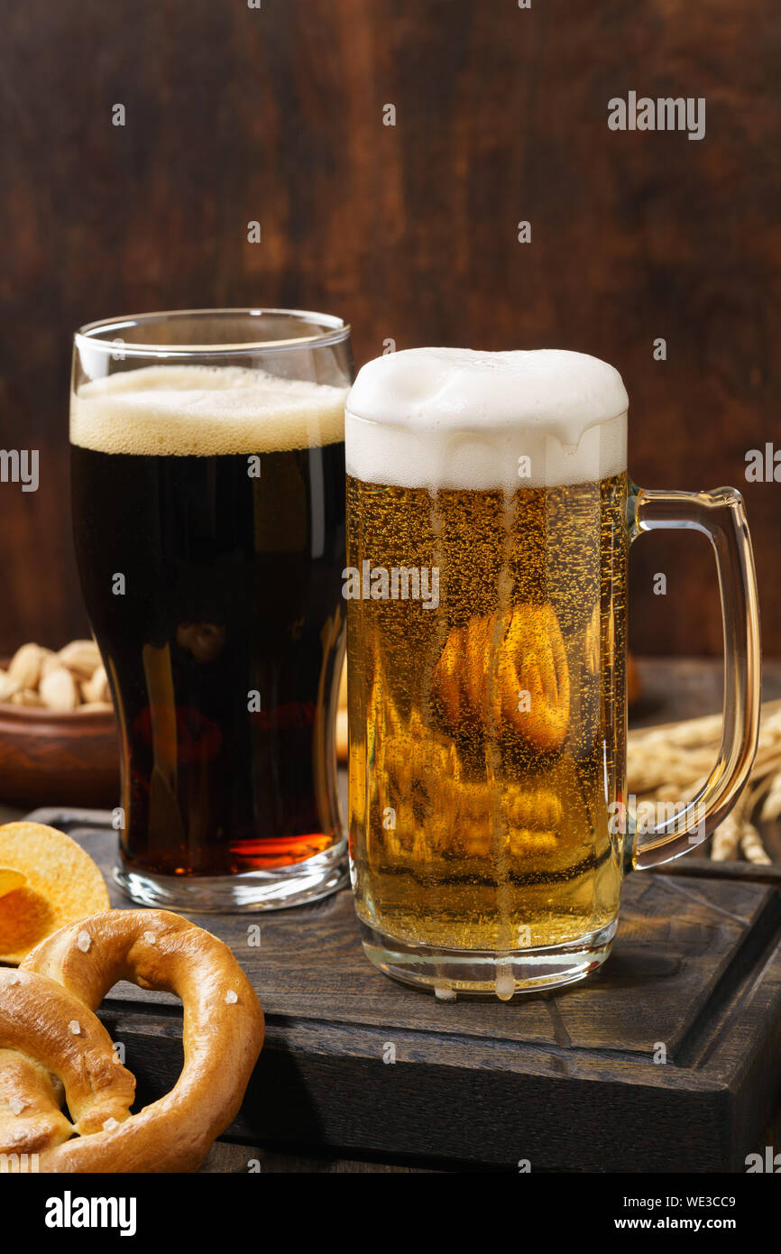 Various types of freshly poured beer - light and dark and snack variety. Dark wooden background. Copy space. Stock Photo