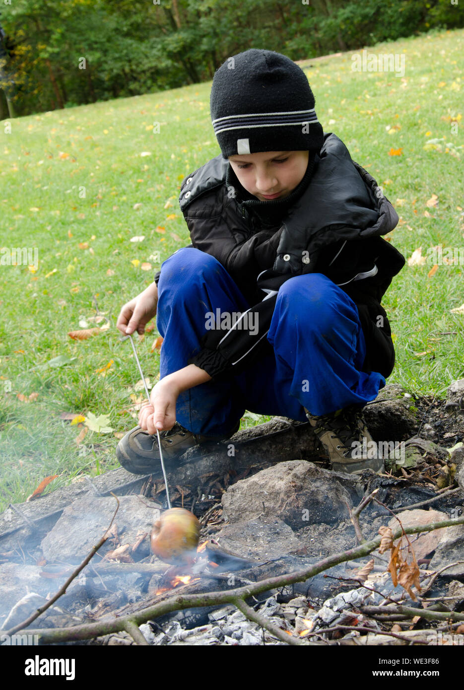 Boy Roasting Apple On Fire Pit Stock Photo